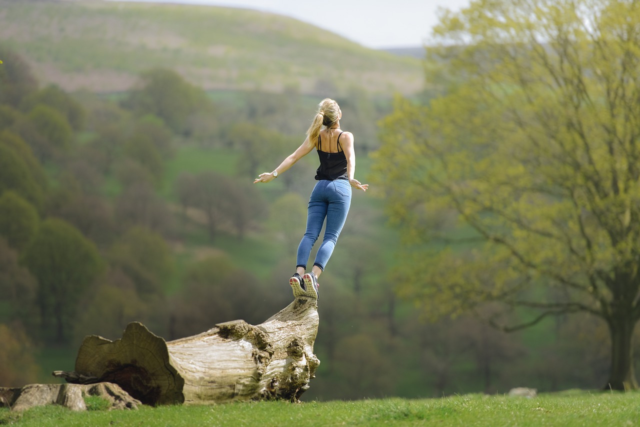 A woman stands on a tree trunk whilst meditating