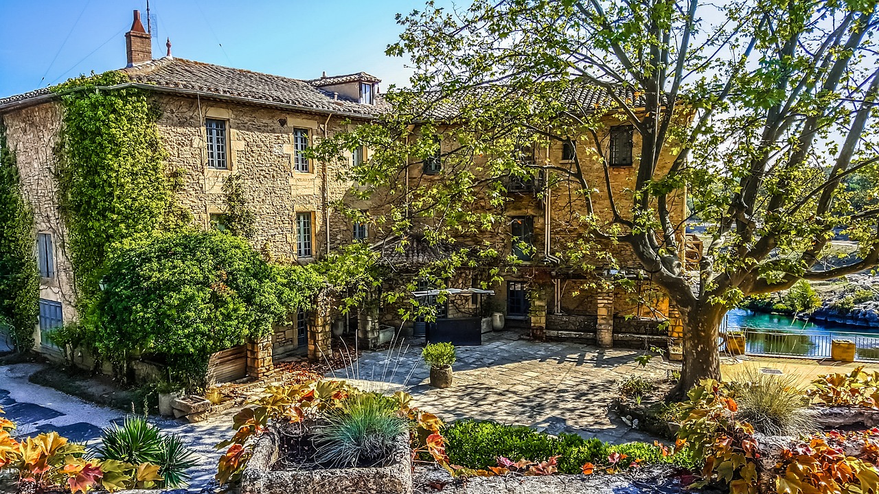 A stone rustic farm house with courtyard garden and trees.