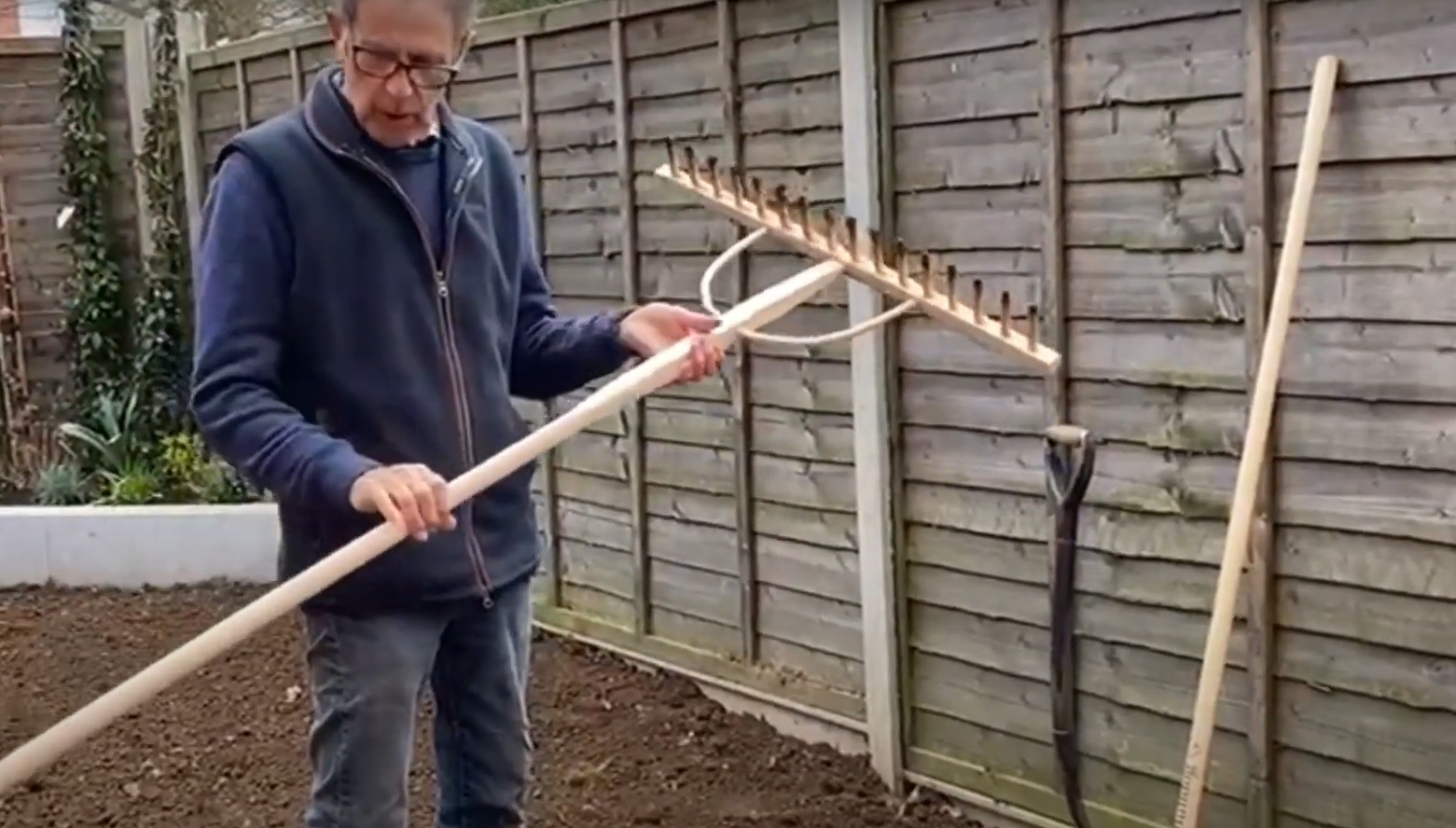 Ken holds a rake and gets ready for turf in a new garden.