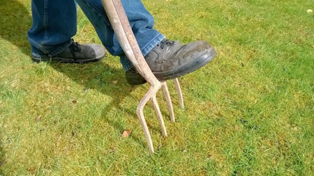 Boot on fork spiking a lawn.